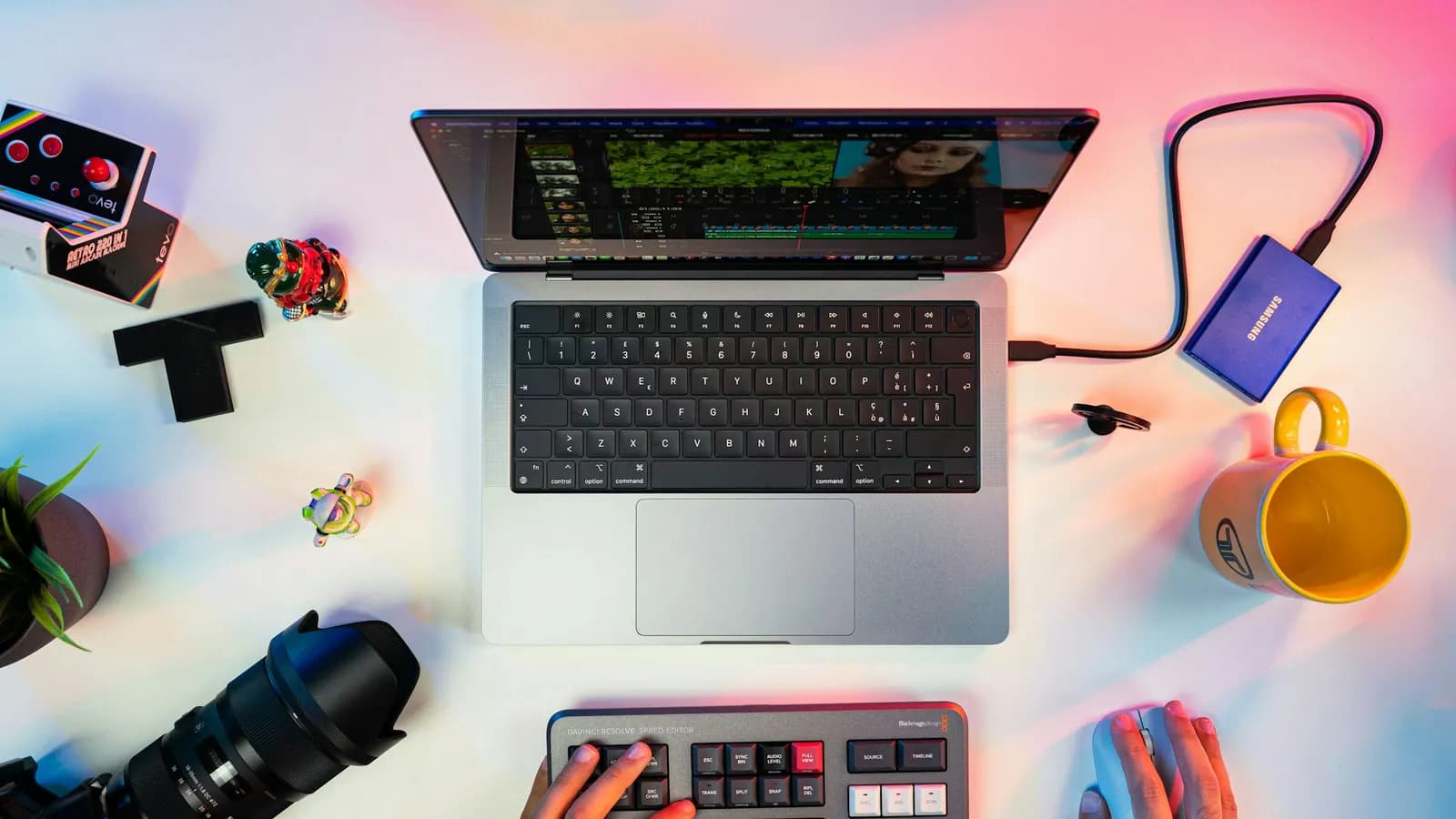 Mesa de criação de conteúdo com notebook, câmera e painel de edição