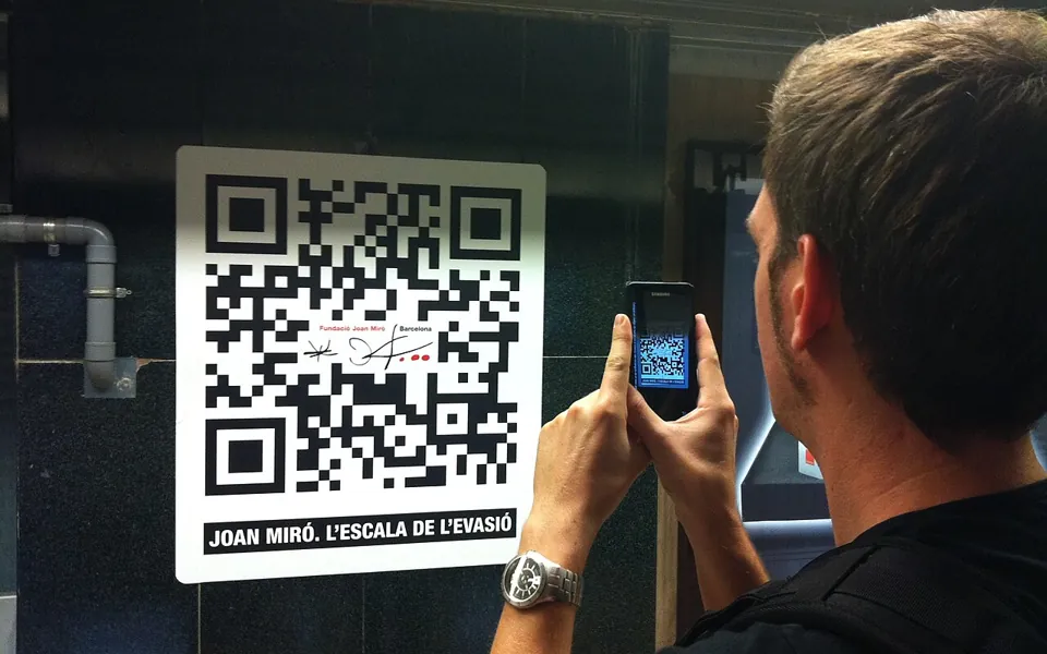 Pessoa usando um celular para escanear um QR Code em um cartaz