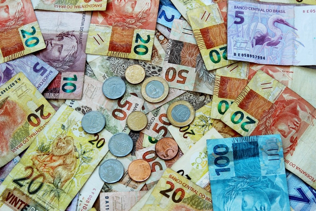 Cédulas e moedas de real espalhadas sobre uma mesa