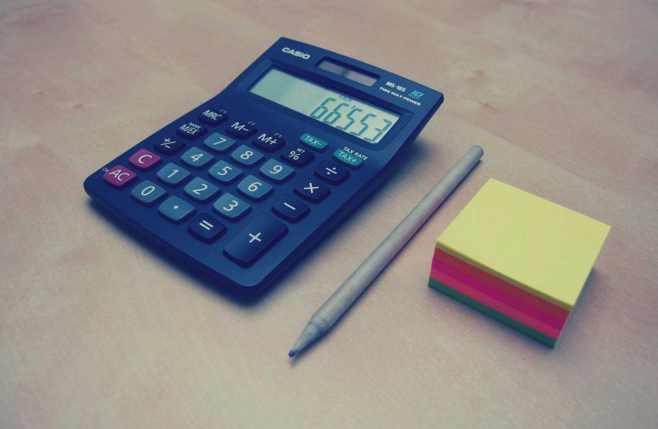 Calculadora, lápis e bloco de notas coloridos sobre uma mesa