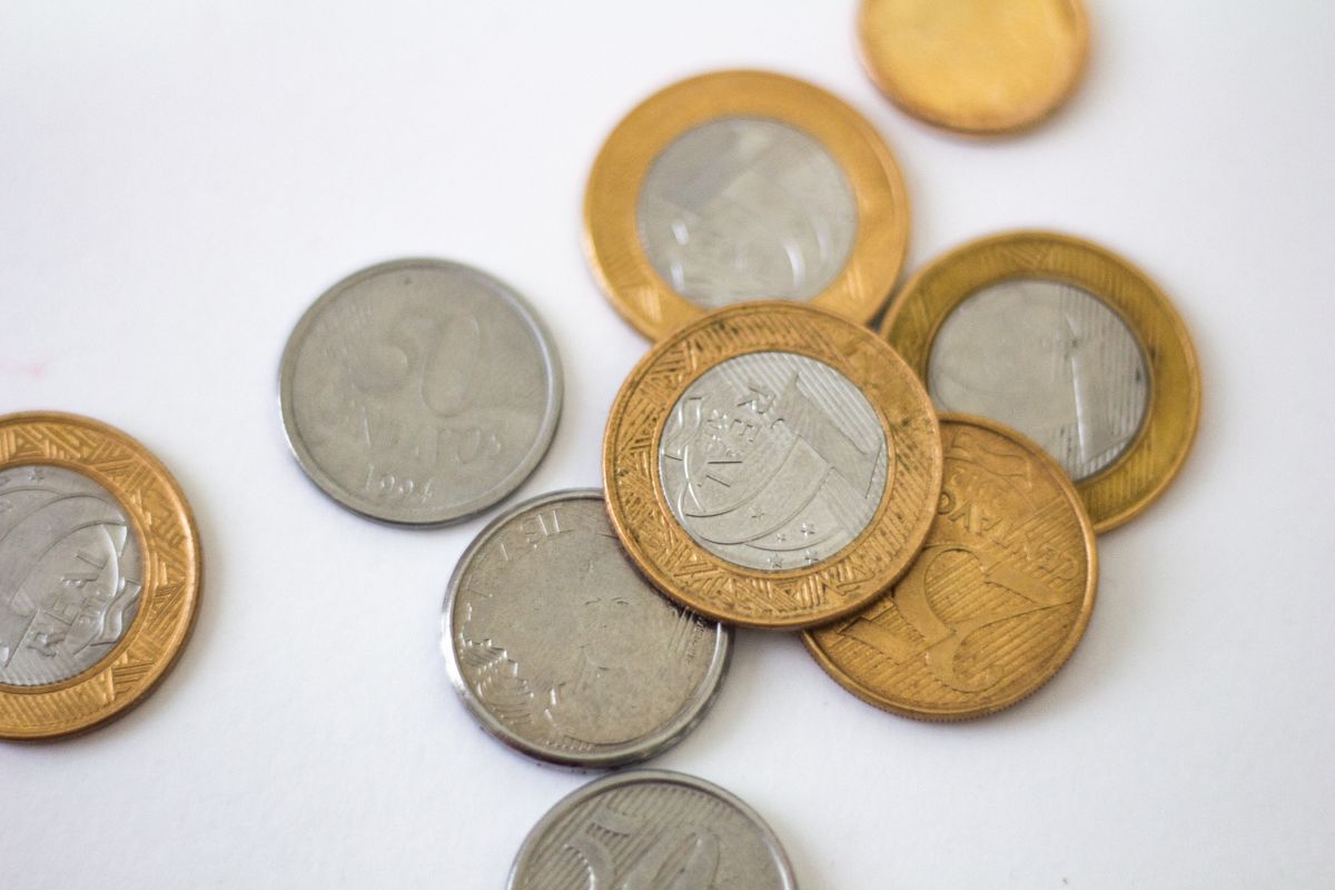Moedas de real espalhadas sobre uma superfície branca