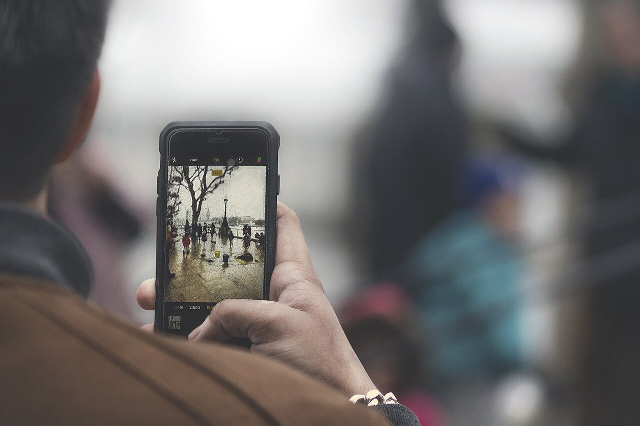 Pessoa segurando o celular na vertical para registrar uma cena na rua